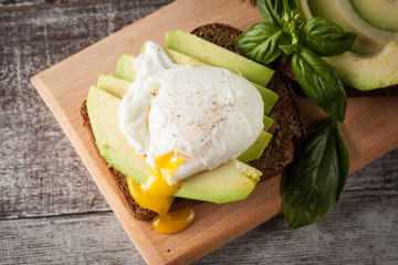 Healthy sandwich with avocado and poached eggs. Healthy food and diet concept.