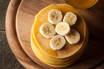 Fresh made delicious pancakes with banana, honey and maple syrup. Healthy morning breakfast concept.