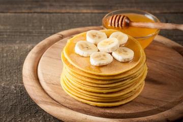 Fresh made delicious pancakes with banana, honey and maple syrup. Healthy morning breakfast concept.