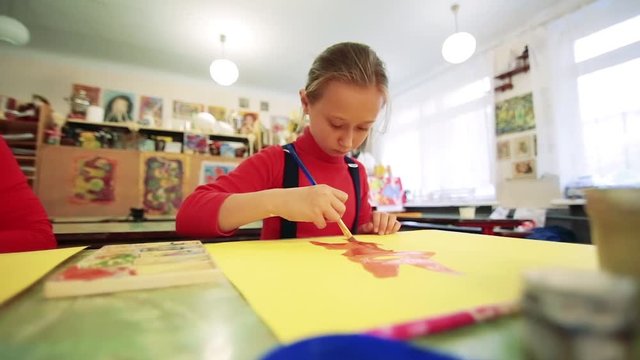 The girl draws a picture paints in classroom