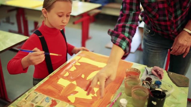 The girl draws a picture paints in classroom