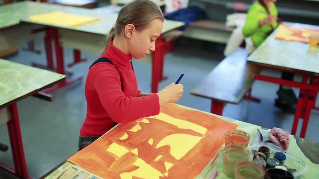 The girl draws a picture paints in classroom