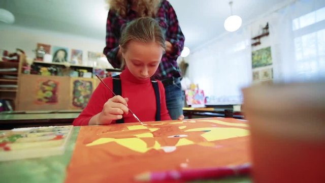 The girl draws a picture paints in classroom