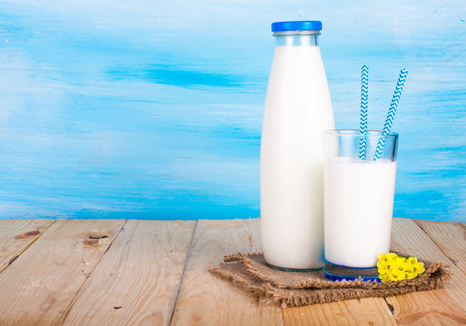 A bottle of milk, a glass of milk with straws. On a blue background.