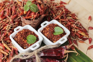 Chili powder and dried peppers on wood background.