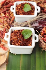 Chili powder and dried peppers on wood background.