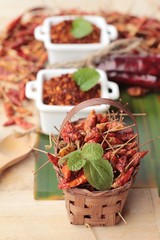 Chili powder and dried peppers on wood background.
