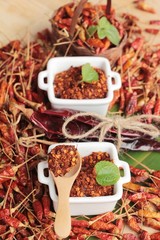 Chili powder and dried peppers on wood background.