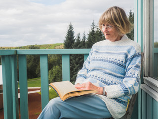 Senior woman is reading at a balcony
