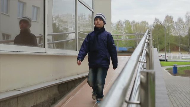 A small boy walking down a wheelchair ramp. Slow motion.