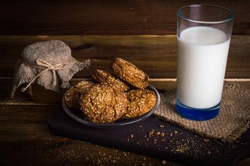 A glass of milk, honey and cookies. On wooden background.