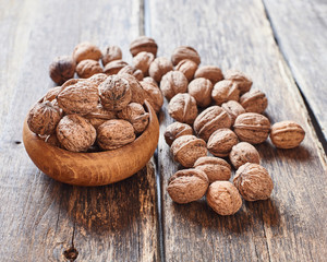 Walnuts in wooden bowl and on vintage wooden table