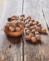 Walnuts in wooden bowl and on vintage wooden table