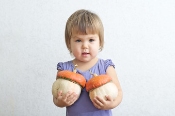 Little child girl with two decorative pumpkins