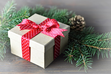 Christmas gift with red bow, spruce branches and pine cone