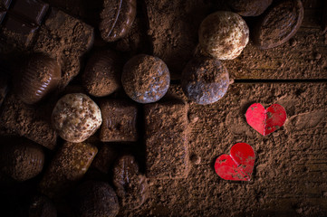chocolate candy in cocoa on a wooden table and two hearts