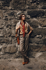 Fashion Model In Fashionable Clothes. Beautiful Woman Near Wall