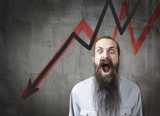 Shouting man with long beard is standing against blackboard with