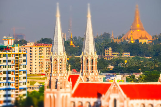 Tilt shift blur effect. Futuristic aerial view panorama of developing Yangon city with catholic Saint Mary’s Cathedral and buddhist Shwedagon Pagoda. Myanmar (Burma) Yangon