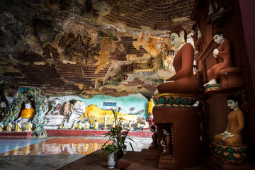 Obraz premium Amazing view of lot Buddhas statues and religious carving on limestone rock in sacred Kaw Goon cave. Hpa-An, Myanmar (Burma) travel landscapes and destinations