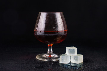 Glass of whiskey with ice on black background