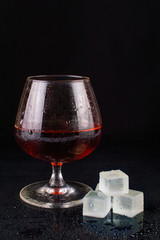 Glass of whiskey with ice on black background