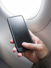 Hand holding cell phone on airplane