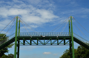 Green sling iron bridge over blue sky