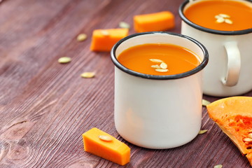 Pumpkin juice in mugs on rustic background
