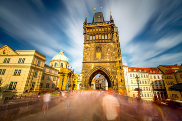 Fototapeta premium View on the tower of Charles bridge in the old town of Prague city. Long exposure image technic with blurred people and clouds