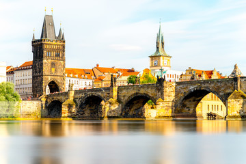 Citycsape view on the riverside with the bridge and old town in Prague. Long exposure image technic with glossy water