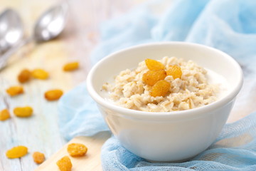 Porridge with raisin and honey in white bowl for breakfast