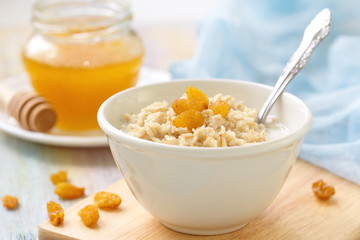 Porridge with raisin and honey in white bowl for breakfast
