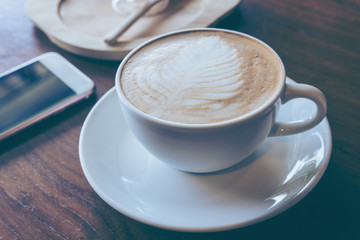 Cup of hot coffee ad smartphone put on old wooden table background