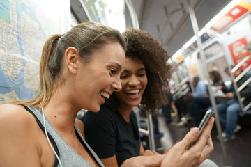 Girls in metro train using smartphone