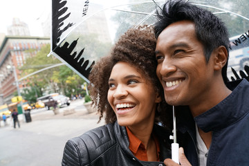 Ethnic couple walking in New york city street on rainy day