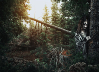 Horror undead woman looks out from behind a tree.