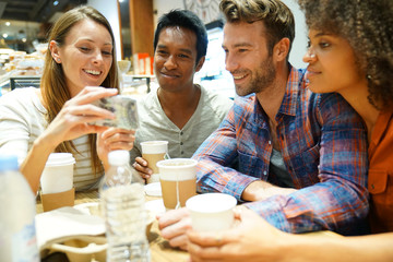 Group of friends in coffee shop looking at smartphone
