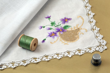 handkerchief, thread, needle and thimble on a gold background