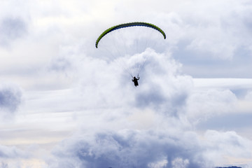 Paraglider flying over mountains in summer day