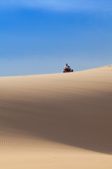 Fototapeta na wymiar ATV quad biking in desert in hot sunny day, Muine sand dunes, Vietnam