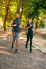 Obraz premium Young couple running on the jogging track through the forest