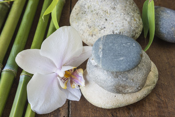 Fototapeta na wymiar Spa concept: orchid flower, spa stones, bamboo on wooden background