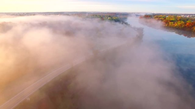 Sunrise over steaming, foggy autumn river, Fall colors adorning shore, aerial view.
