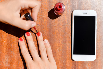 Top view on cell phone and hands doing manicure. Close up table mockup background