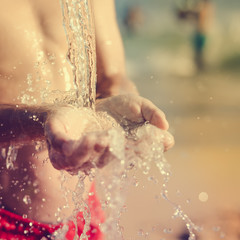 Hand and water, wet sand blurry outdoors background, close up image