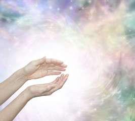 Faith Healing with Blissful Energy - Outstretched female healing hands surrounded by a large radiating circle of white light and a subtle pastel colored ethereal energy field in background 