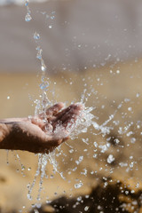 Closeup on hands with water splash, sun light background outdoors
