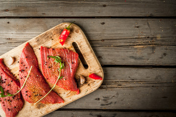 Fresh raw meat. Spices, chilli and garlic. Beef steak on a cutting board on a wooden table. Top view