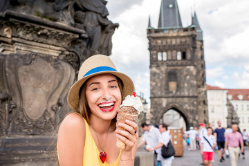 Naklejka premium Young female tourist with traditional czech dessert called trdelnik on Charles bridge in Prague